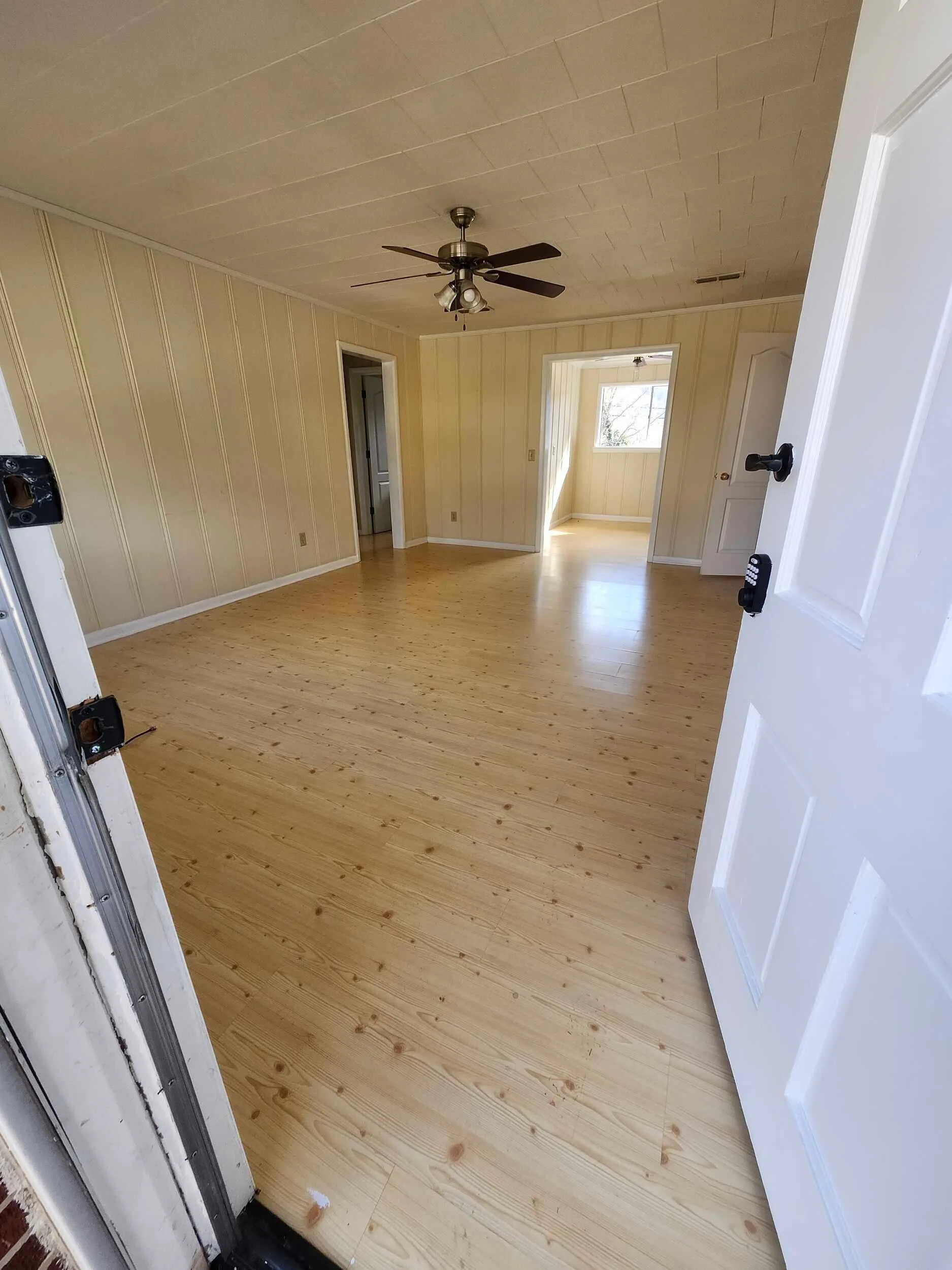 Bright Brickstone Square room with wood floors, paneled walls, and a ceiling fan