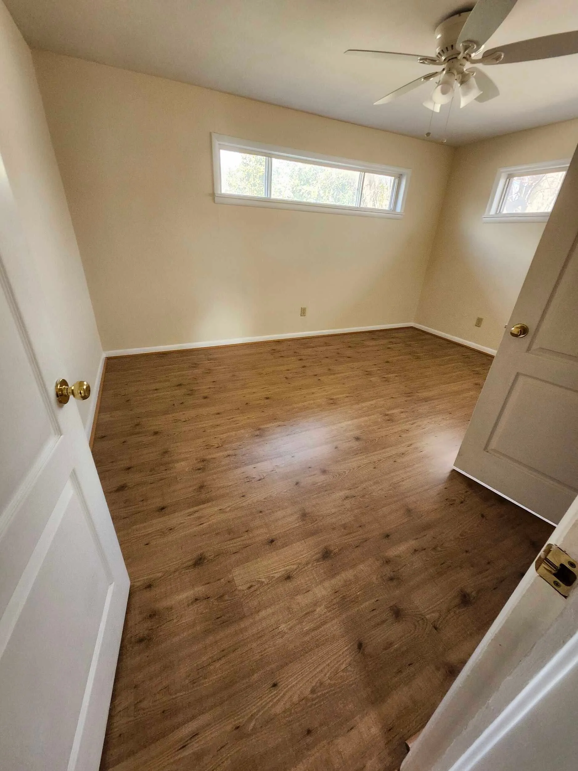 Brickstone Square room with warm wood floors, paneled walls, and high windows