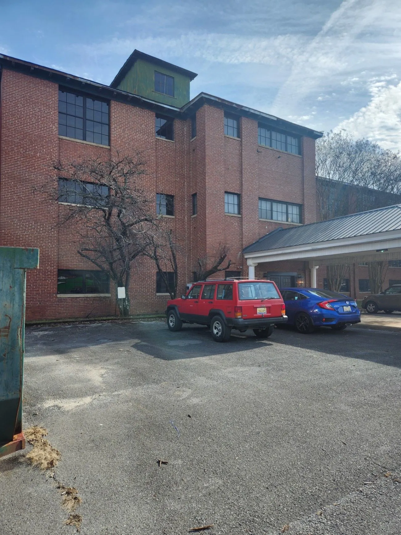 Brick Mill Town building with parked cars and a covered entrance