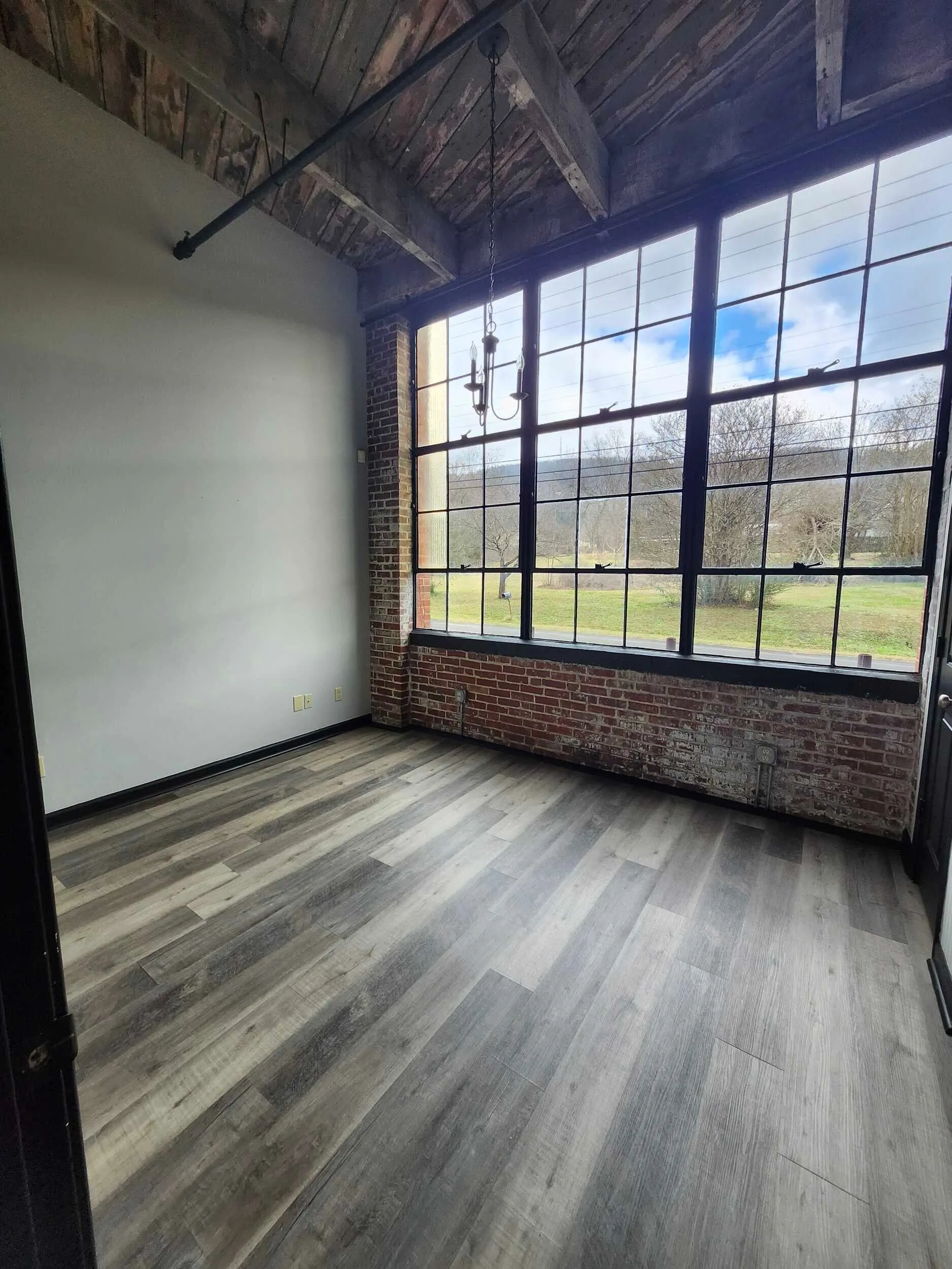 Interior room with wood-look flooring and a large industrial-style window